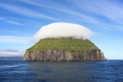 Uninhabited small island covered by a cap of clouds